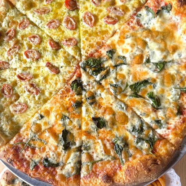 A large pizza from Casa Mia, half with cherry tomatoes and half with spinach and cheese.